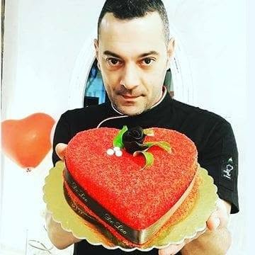 Gianluca De Leo mostra una torta a forma di cuore, decorata con crema rossa e una rosa di cioccolato
